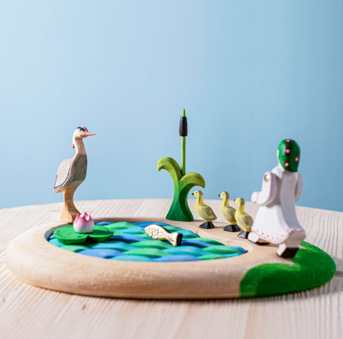 Ensemble lac, quenouilles, nénuphar, poisson, héron, fille et canetons